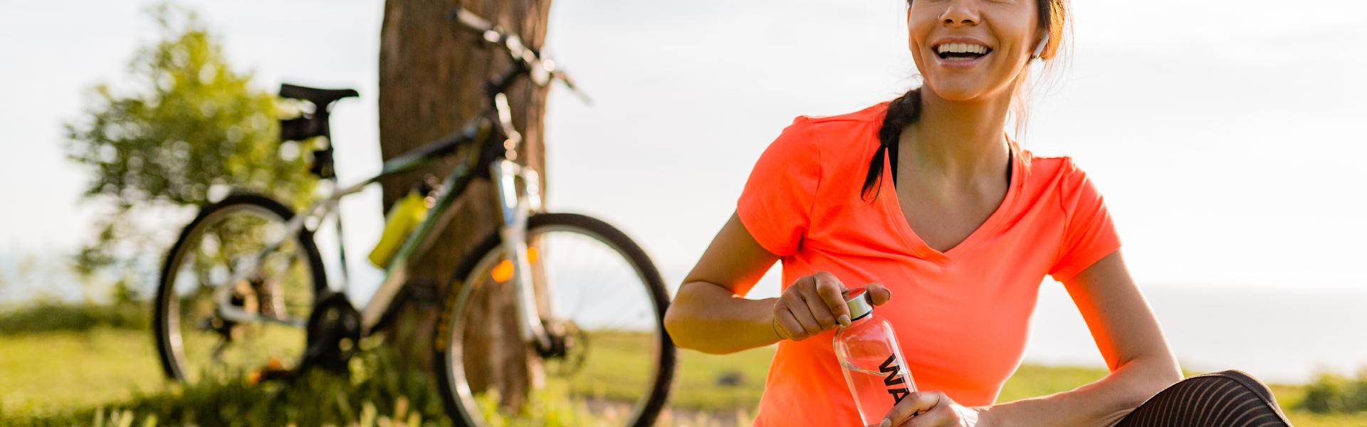 healthy woman with bike and drinking water